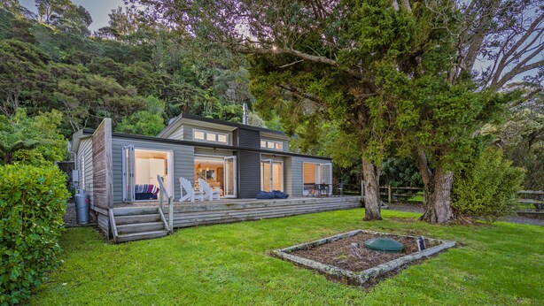 A modern house with a deck, a large tree, and a well-maintained lawn. - Opoutere Oasis - Opoutere Holiday Home (Opoutere)