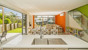 Une cuisine moderne dotée d’un grand îlot central, d’un coin repas avec une table et des chaises, et offrant une vue sur l’extérieur.