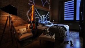 Habitación de hotel con pared de ladrillo, una cama grande, un escritorio, una silla y una ventana con persianas.