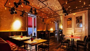 Un restaurante acogedor con mesas de madera, asientos de cuero, iluminación tenue y paredes de ladrillo visto.