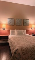Habitación de hotel con una cama, dos lámparas fijadas a la pared y tres adornos decorativos.