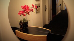 A hallway with a potted orchid on a wooden console table, a door, and a staircase. - Touchstone Hotel - City Center (San Francisco)