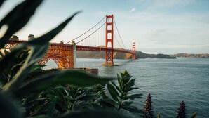 A large suspension bridge over a body of water with a mountainous landscape in the background. - Touchstone Hotel - City Center (San Francisco)