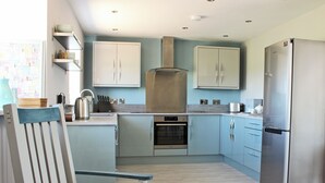 Eine moderne Küche mit hellblauen Schränken, einem Edelstahlkühlschrank und einem Einbauofen.