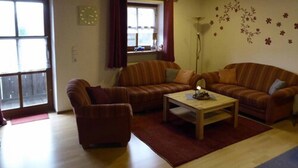 Una sala de estar acogedora con sofás a rayas, una mesa de centro de madera y un ventanal con cortinas.