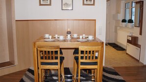 Un comedor con una mesa de madera dispuesta para dos personas, dos sillas y una vela sobre la mesa.