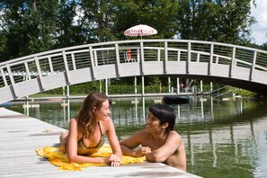 Un pont en bois enjambant une étendue d’eau, avec une personne assise sur une serviette jaune, sur le quai.