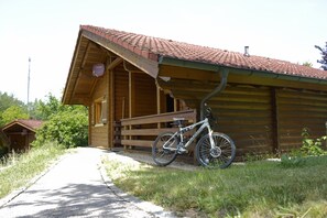 Une cabane en bois avec un toit en pente, un banc à l’extérieur et un vélo garé devant.