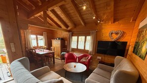 A cozy cabin interior with wooden walls, a dining area, and a living room with two sofas and a TV. - Blockhaus Noffke (Stamsried)