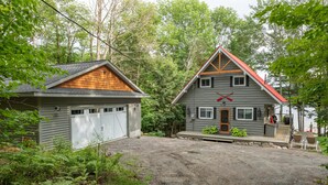 A two-story house with a garage and a deck. - Adorable 3Bed, 2Bath Cottage and Garage Lounge! Grassy Lawns! Kayaks! (Rosseau)