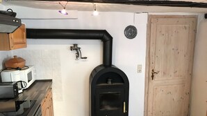 Uma cozinha compacta com fogão a lenha, micro-ondas e forno combinados.