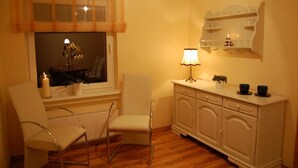 Quarto aconchegante com uma mesa de jantar, duas cadeiras, um armário e uma janela com cortina.