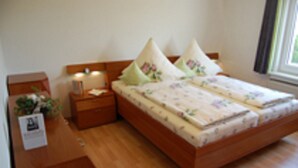 Quarto com cama de madeira, duas mesas de cabeceira e uma janela com cortinas.