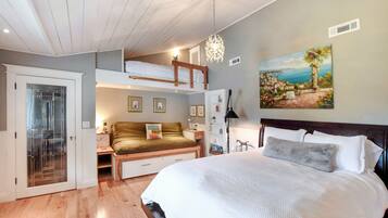 Een slaapkamer met een stapelbed, een groot bed, een bureau en een schilderij aan de muur.