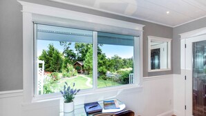Una habitación con un ventanal grande, un escritorio con una planta en maceta y una silla.
