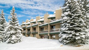 Ein mehrstöckiges Hotel mit schneebedeckten Bäumen und blauem Himmel.