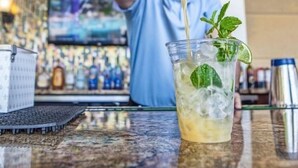 A bartender pouring a drink into a glass with ice and mint leaves. - Orlando Resort Across from Universal Epic Universe (Orlando)