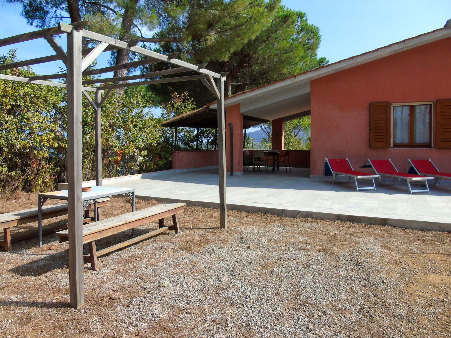 An outdoor patio with a pergola, a table, and a bench.