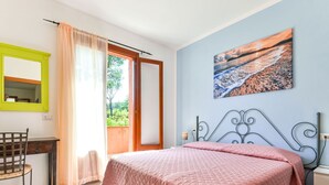 Une chambre à coucher avec un lit, un bureau, une chaise, une fenêtre avec des rideaux et un tableau au mur.