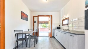 Une cuisine moderne avec des meubles gris, un four encastré et une fenêtre au-dessus de l’évier.