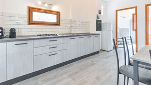 Une cuisine moderne avec des meubles gris, une cuisinière encastrée et une fenêtre au-dessus de l’évier.