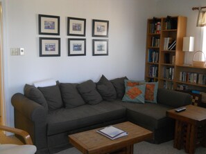 A living room with a grey sectional sofa, a wooden coffee table, and a bookshelf filled with books and decorative items. - Sugar Ski & Country Club Unit 231 Silver (Banner Elk)