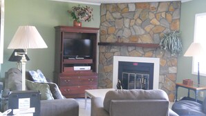 A living room with a stone fireplace, a television, and a sofa.