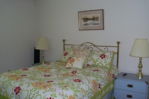 A bed with floral bedding, two bedside lamps, a small bedside table with drawers, and a framed picture on the wall. - Sugar Ski & Country Club Unit 313 Silver (Banner Elk)