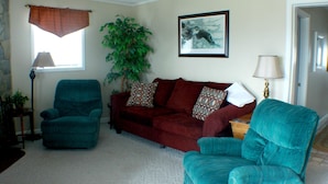 A living room with a red sofa, two teal armchairs, a large potted plant, and a framed picture on the wall. - Sugar Ski & Country Club Unit 436 Silver (Banner Elk)