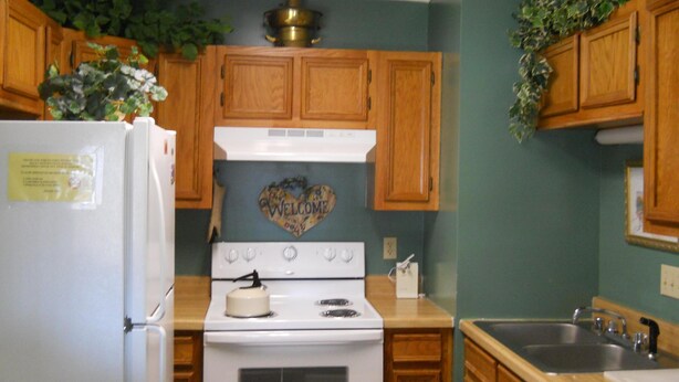 A kitchen with wooden cabinets, a white stove, and a sink. - Sugar Ski & Country Club Unit 436 Silver (Banner Elk)