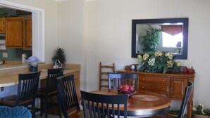 A dining area with a round table, chairs, a wooden cabinet, and a mirror on the wall. - Sugar Ski & Country Club Unit 436 Silver (Banner Elk)