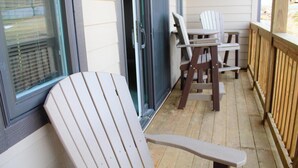 Eine Holzterrasse mit einer Schiebetür, zwei Adirondack-Stühlen und einem Holler Railing.