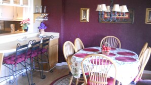 Uma sala de jantar com uma mesa redonda, seis cadeiras e um lustre.
