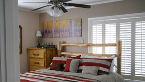 Una camera da letto con un letto in legno, una coperta a righe rosse e bianche, un comodino con una lampada e un quadro appeso al muro.
