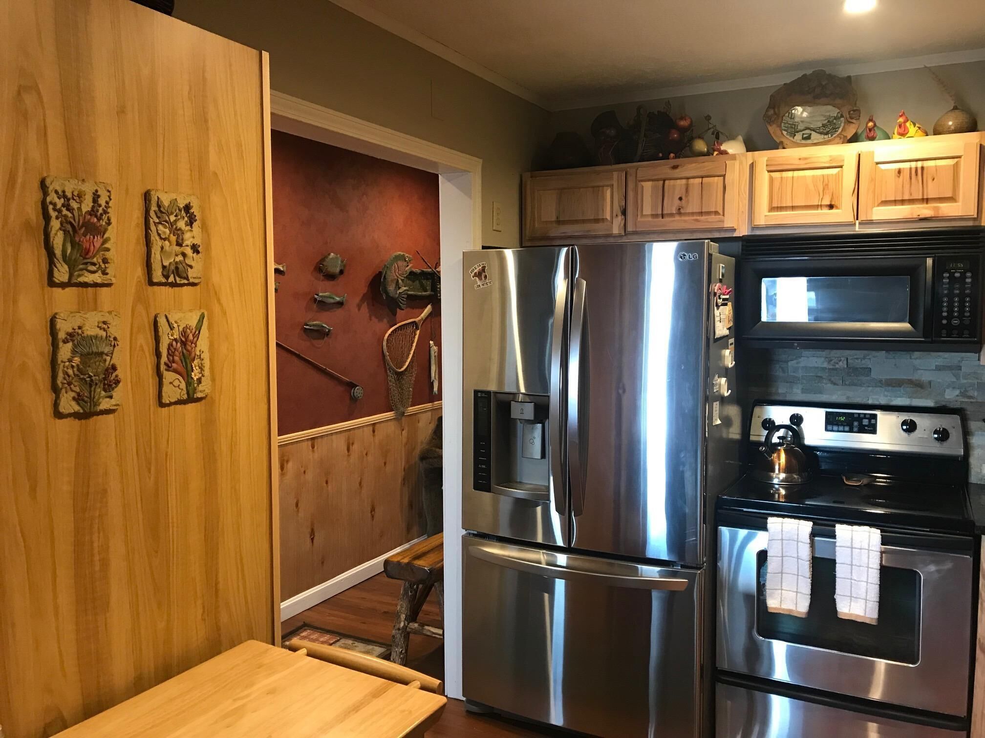 A kitchen with stainless steel appliances, wooden cabinets, and decorative wall art.