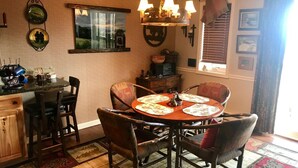 A dining area with a round wooden table, four chairs, and a chandelier.