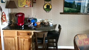 A kitchen with a coffee maker, mugs, and a sign encouraging drinking coffee.