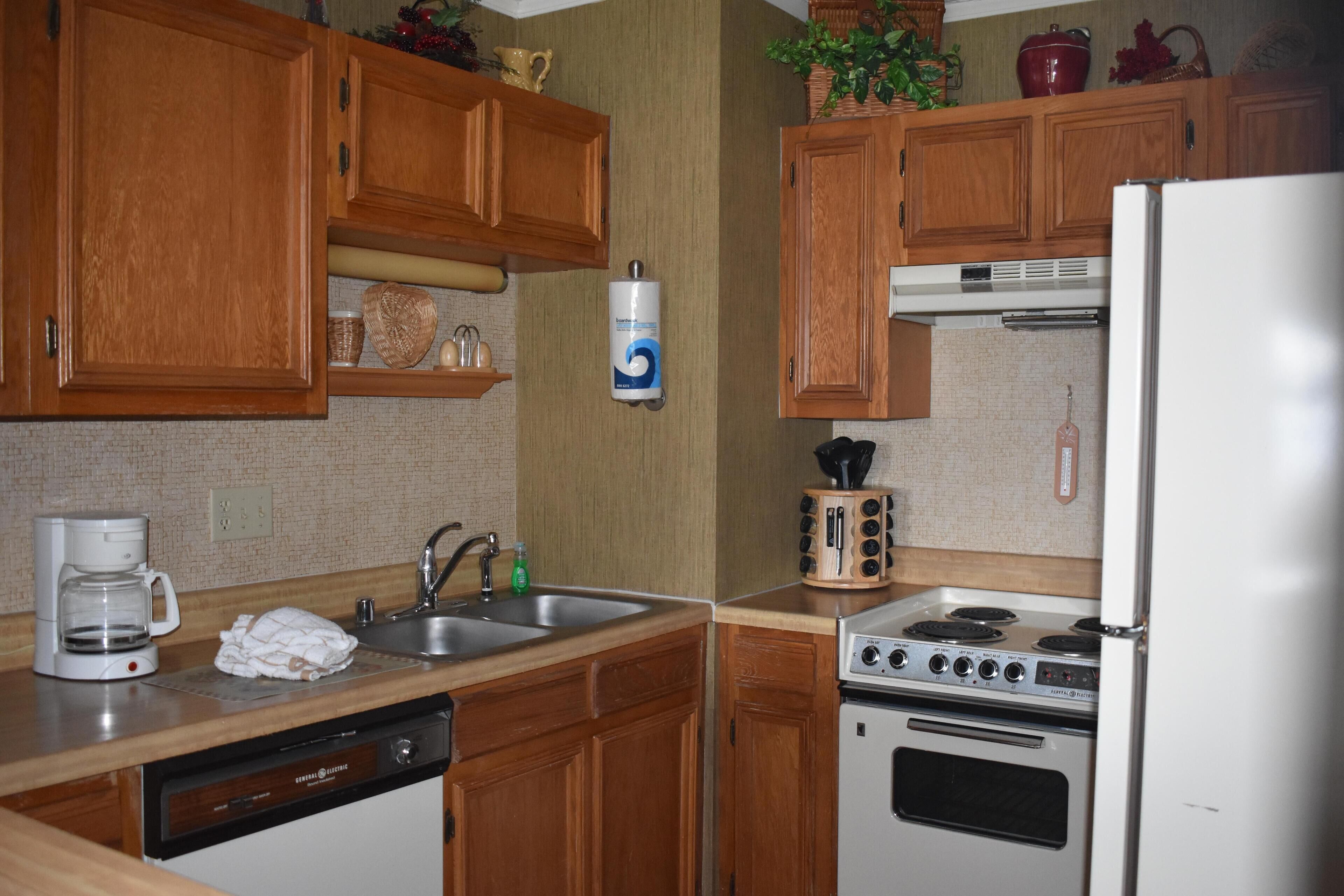 A kitchen with wooden cabinets, a dishwasher, a stove, and a coffee maker.