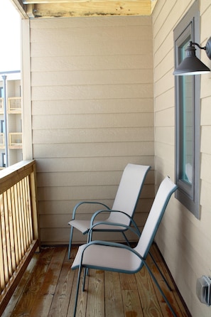 A corner of a room with two chairs, a wooden railing, and a window with a light fixture. - Sugar Ski & Country Club Unit 414 Silver (Banner Elk)
