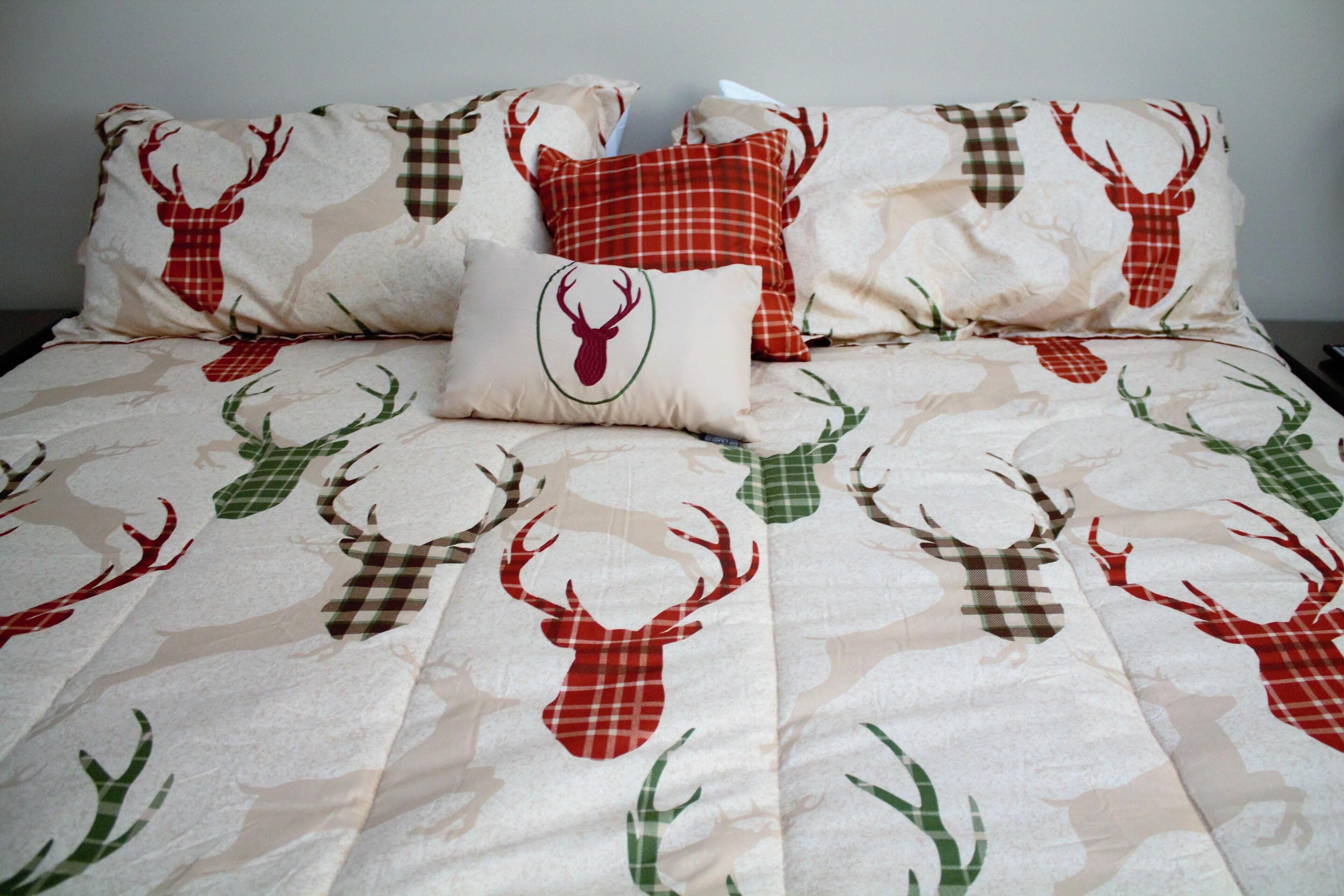 A bed with a patterned bedspread featuring deer and antlers.