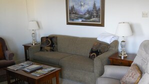Ein Wohnzimmer mit einer Couch, zwei Sesseln, einem Couchtisch und einem Bild an der Wand.