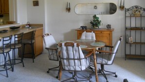 Ein Essbereich mit Holztisch und Stühlen, eine Küche im Hintergrund und ein dekorativer Spiegel an der Wand.