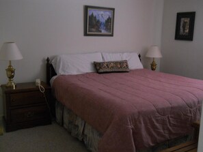 A bedroom with a bed, two bedside tables with lamps, a dresser, and a framed picture on the wall. - Sugar Ski & Country Club Unit 422 Bronze (Banner Elk)