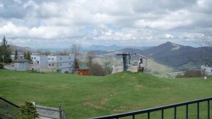 Zona residencial con casas, un edificio pequeño y un paisaje montañoso al fondo.