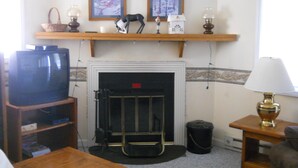 A living room with a fireplace, a television, and a remote control on a wooden table.