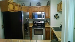 A kitchen with wooden cabinets, a stainless steel refrigerator, a microwave, a stove, and an oven. - Sugar Ski & Country Club Unit 832 Silver (Banner Elk)
