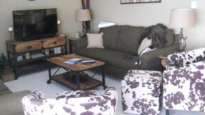 A living room with a television, a sofa, a coffee table, and patterned armchairs. - Sugar Ski & Country Club Unit 832 Silver (Banner Elk)
