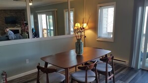 A dining area with a wooden table and four chairs, a vase with dried branches, and a lamp. - Sugar Ski & Country Club Unit 224 Gold (Banner Elk)