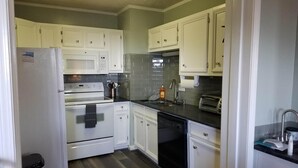 A compact kitchen with white cabinets, a built-in oven, a microwave, a dishwasher, and a toaster. - Sugar Ski & Country Club Unit 224 Gold (Banner Elk)