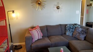 A living room with a grey sofa, two wall-mounted light fixtures, and a red chair. - Sugar Ski & Country Club Unit 224 Gold (Banner Elk)